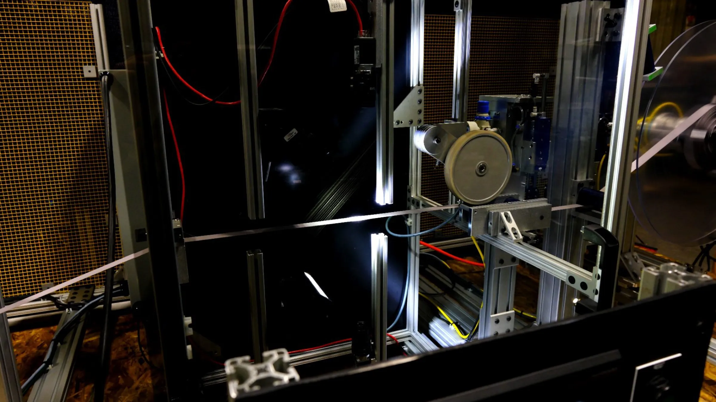 Inside a Shelfmark inspection frame on a webbing line: a strip of webbing running horizontally between backlit inspection bars, with the cameras aimed at it through the guard glass.